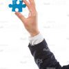 Man's Hand Holding Small Blue Piece Of Puzzle Stock Photo