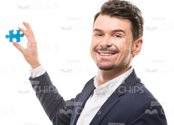 Smiling Man Showing Small Piece of Puzzle Stock Photo