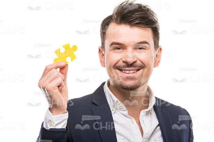 Happy Guy Dressed In Formal Suit Holding Puzzle Piece Stock Photo
