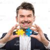 Happy Man Connects Two Puzzle Pieces Stock Photo