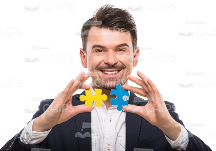Happy Man Connects Two Puzzle Pieces Stock Photo