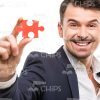 Self-Confident Young Man Showing The Red Piece Of Puzzle Stock Photo