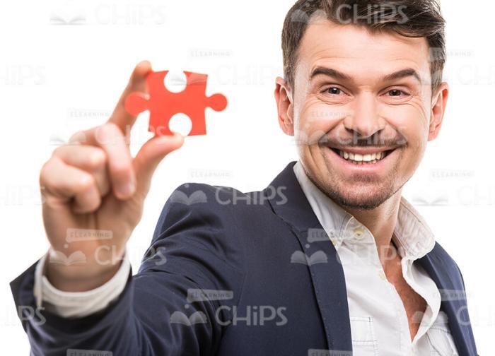 Self-Confident Young Man Showing The Red Piece Of Puzzle Stock Photo