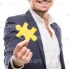 Man Holds Yellow Piece Of Puzzle With Right Hand Stock Photo