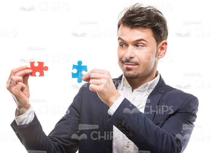 Attentive Man Going To Connect Puzzle Pieces Stock Photo