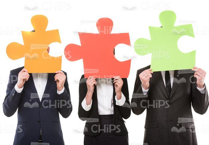 Business People Covering Heads With Large Puzzle Pieces Stock Photo