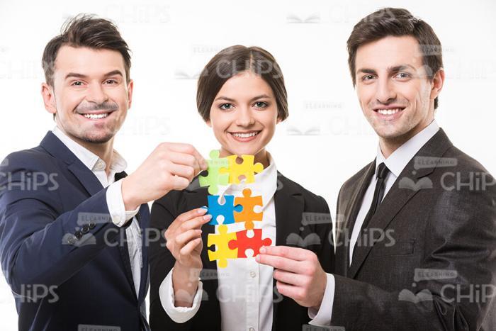 Smiling Business People Assembling Puzzles Stock Photo