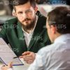 Bearded Business Man Pointing With Pen At Clipboard Stock Photo