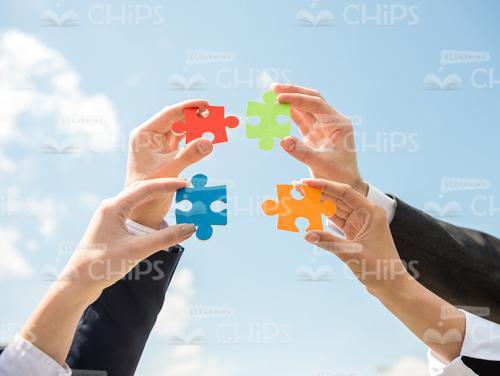 Four Small Colored Pieces Of Puzzle On Sky Background Stock Photo