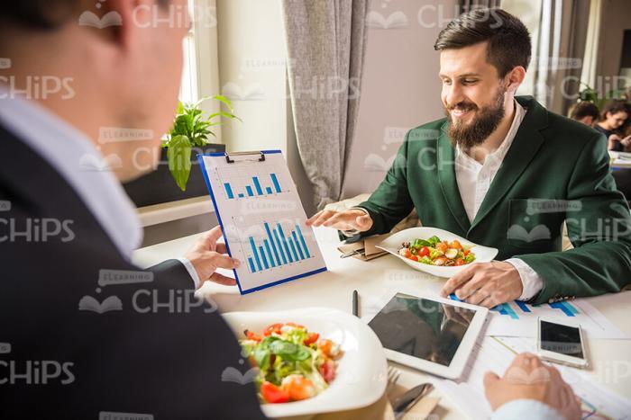 DIscussing Graphs During Business Lunch Stock Photo