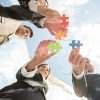 Four People Connecting Puzzle Pieces Stock Photo