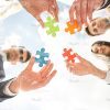 Business Team Holding Four Colored Puzzle Pieces Stock Photo