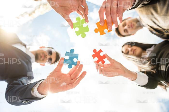 Business Team Holding Four Colored Puzzle Pieces Stock Photo