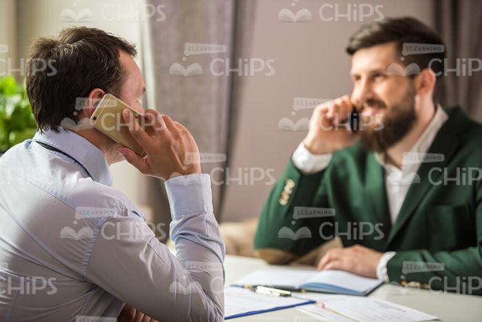 Businessmen Talking On Phones During Lunch Time Stock Photo