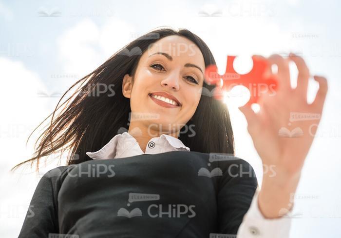 Cute Businesswoman Holding Red Jigsaw Puzzle Stock Photo