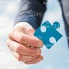 Man's Hand Holding Blue Piece Of Puzzle Stock Photo