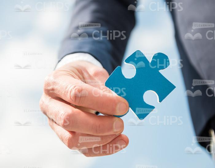 Man's Hand Holding Blue Piece Of Puzzle Stock Photo
