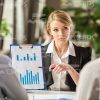 Young Businesswoman Holding Clipboard And Pointing On Charts Stock Photo