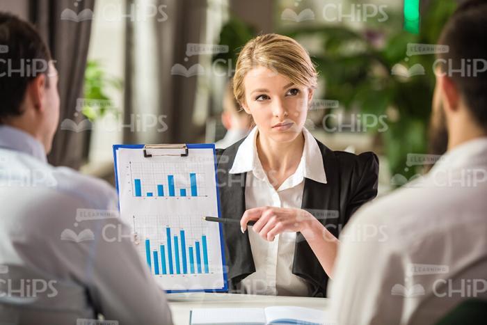 Young Businesswoman Holding Clipboard And Pointing On Charts Stock Photo
