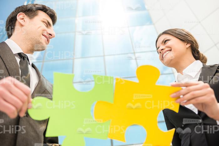 Couple Of Business Persons Holding Colored Jigsaw Puzzle Stock Photo