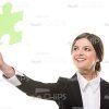 Green Puzzle Piece In Woman's Outstretched Hand Stock Photo