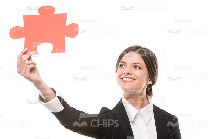 Young Woman Raising Up Red Colored Piece Of Puzzle Stock Photo