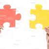 Hands Holding Red And Yellow Puzzle Pieces Stock Photo