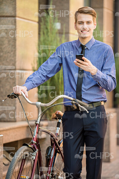 Nice Young Businessman Using The Phone And Holding His Bicycle Stock Photo