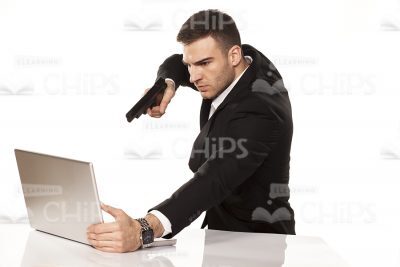 Young Businessman With Gun Pointed At Laptop Stock Photo-0