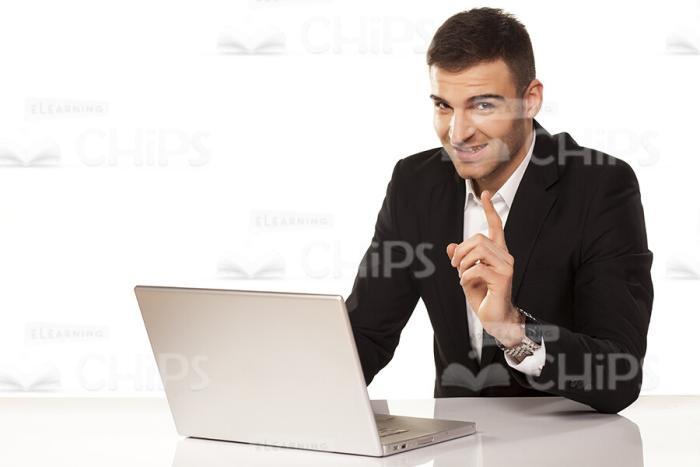 Smiling Businessman At Workplace Pointing Upwards Stock Photo-0