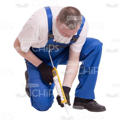 Crouching Worker Using Construction Sealant Cutout Image-0